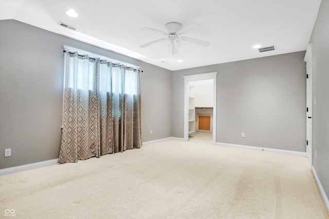 spare room with a ceiling fan, light colored carpet, and visible vents