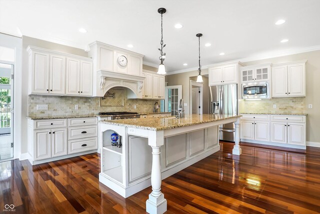 kitchen featuring white cabinetry, dark wood-type flooring, pendant lighting, stainless steel appliances, and a center island with sink