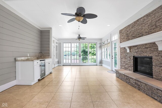 kitchen with white cabinets, a fireplace, light stone countertops, ceiling fan, and french doors