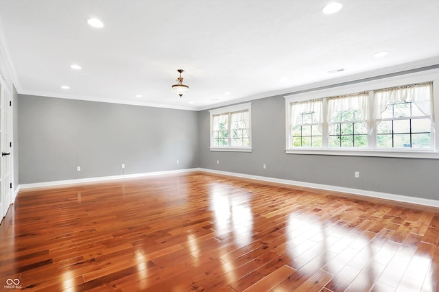 spare room featuring baseboards, crown molding, and wood finished floors