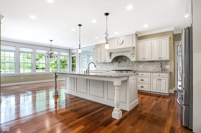 kitchen with a center island with sink, dark hardwood / wood-style floors, a kitchen breakfast bar, and white cabinetry