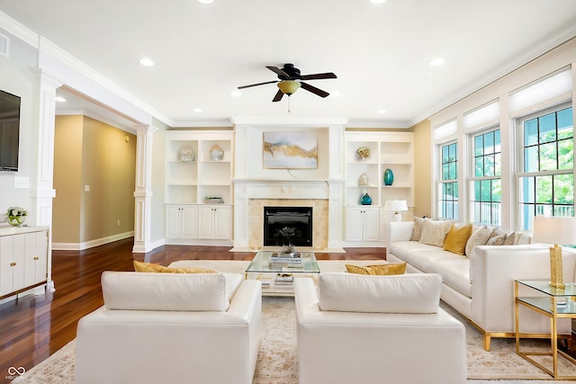 living room with ornamental molding, wood finished floors, a tiled fireplace, and a ceiling fan