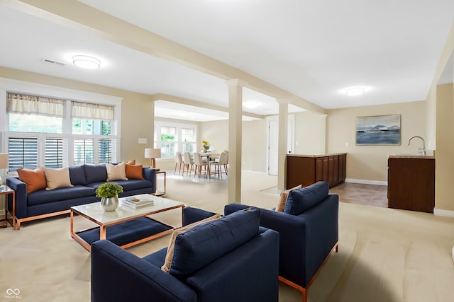 living room with decorative columns, baseboards, and visible vents