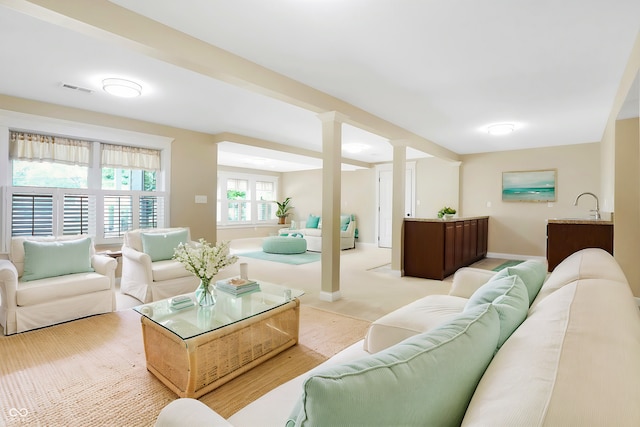 carpeted living room featuring sink and ornate columns