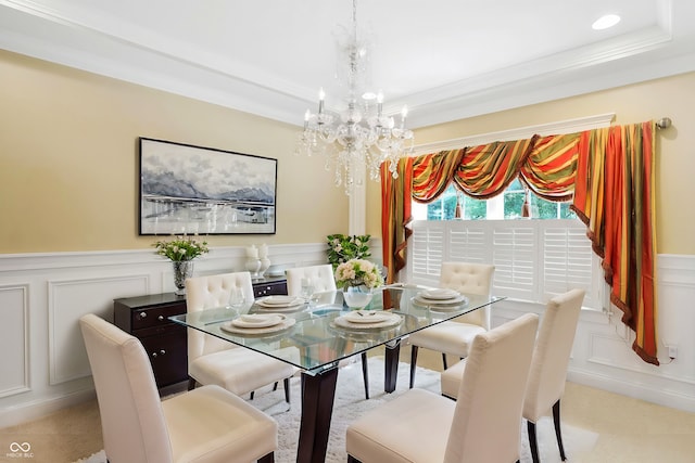 dining space featuring light colored carpet, ornamental molding, a tray ceiling, and a chandelier