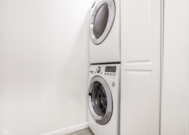 washroom with stacked washing maching and dryer and light tile patterned floors