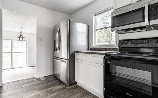 kitchen featuring wood-type flooring, hanging light fixtures, white cabinetry, and stainless steel appliances