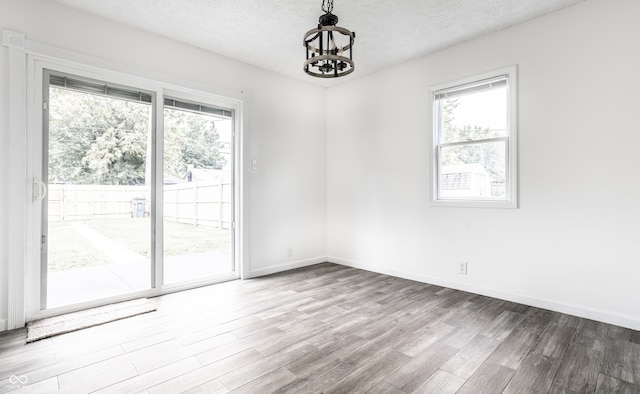 spare room with hardwood / wood-style flooring, a textured ceiling, and an inviting chandelier