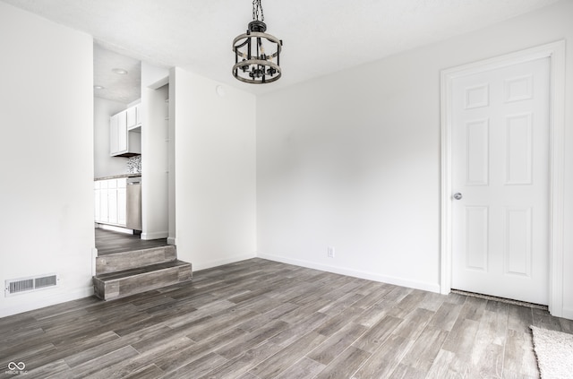 spare room featuring hardwood / wood-style floors and an inviting chandelier