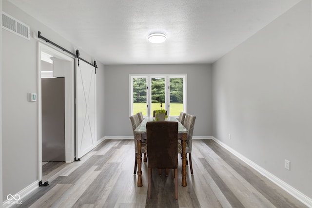 dining room featuring light wood-type flooring and a barn door