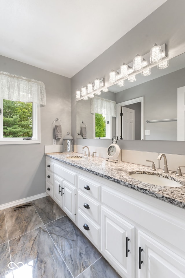 bathroom with double vanity, tile patterned flooring, and a wealth of natural light