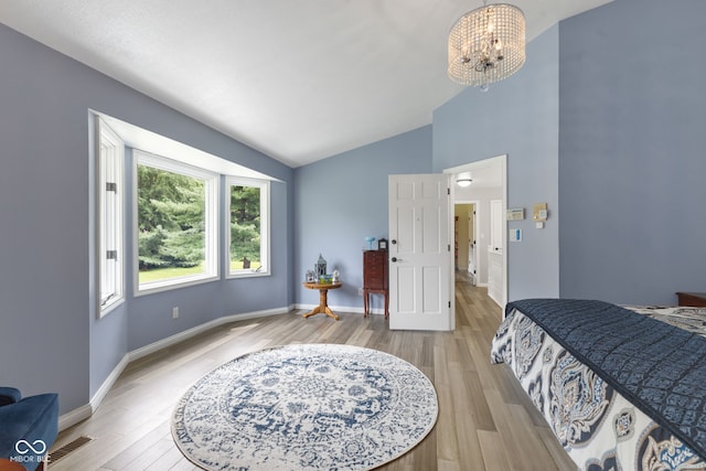 bedroom featuring an inviting chandelier, light wood-type flooring, and lofted ceiling