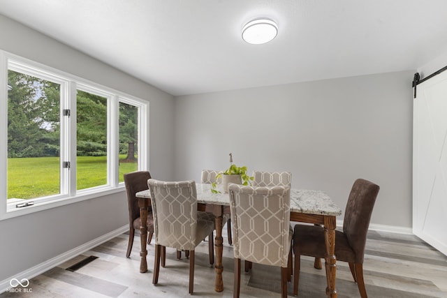 dining room with a barn door and light wood-type flooring