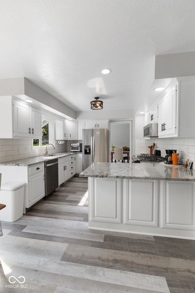 kitchen featuring backsplash, light hardwood / wood-style flooring, appliances with stainless steel finishes, and white cabinetry