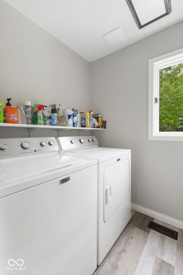 washroom featuring a textured ceiling, independent washer and dryer, and light hardwood / wood-style floors