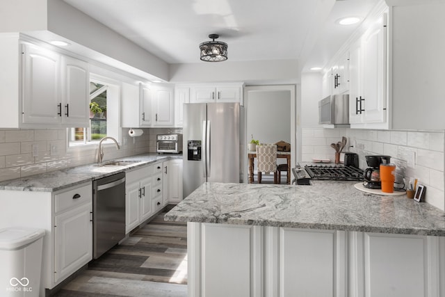 kitchen with stainless steel appliances, dark hardwood / wood-style flooring, decorative backsplash, white cabinetry, and kitchen peninsula