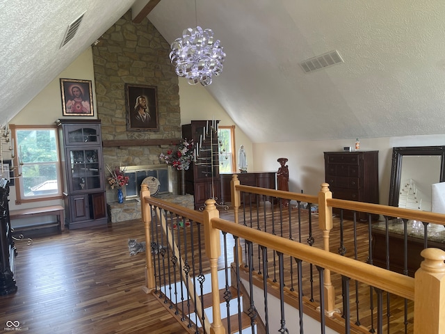 hallway featuring a textured ceiling, lofted ceiling, dark wood-type flooring, and an inviting chandelier