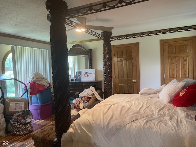 bedroom featuring a textured ceiling, ceiling fan, crown molding, and wood-type flooring