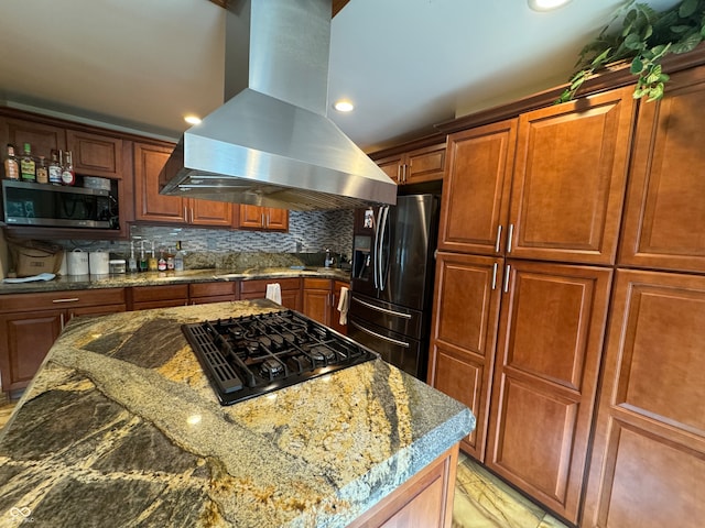 kitchen with backsplash, light stone counters, island range hood, and black appliances