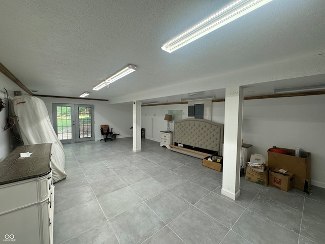 basement with a textured ceiling, french doors, and light tile patterned flooring