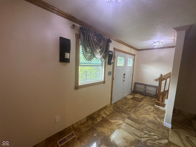 foyer with tile patterned floors, a textured ceiling, and ornamental molding