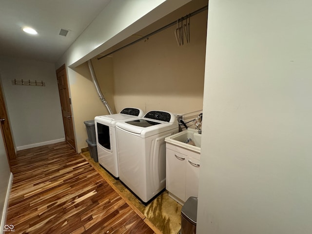 washroom with hardwood / wood-style flooring and washing machine and clothes dryer