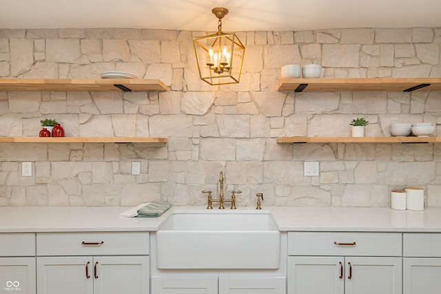 kitchen with sink, white cabinetry, an inviting chandelier, and pendant lighting