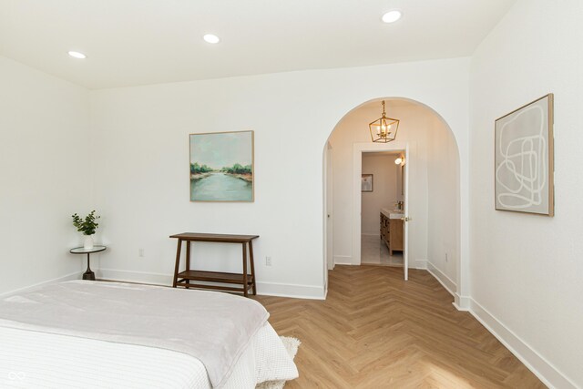 bedroom featuring light parquet flooring and ensuite bathroom