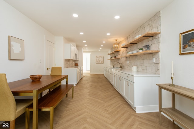 kitchen featuring sink, white cabinetry, tasteful backsplash, and light parquet flooring