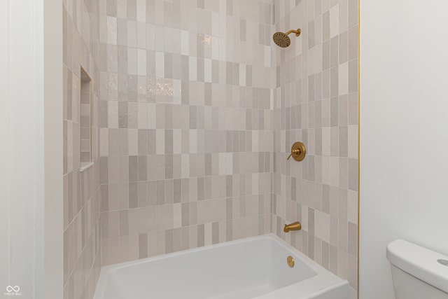 bathroom featuring tiled shower / bath combo and toilet