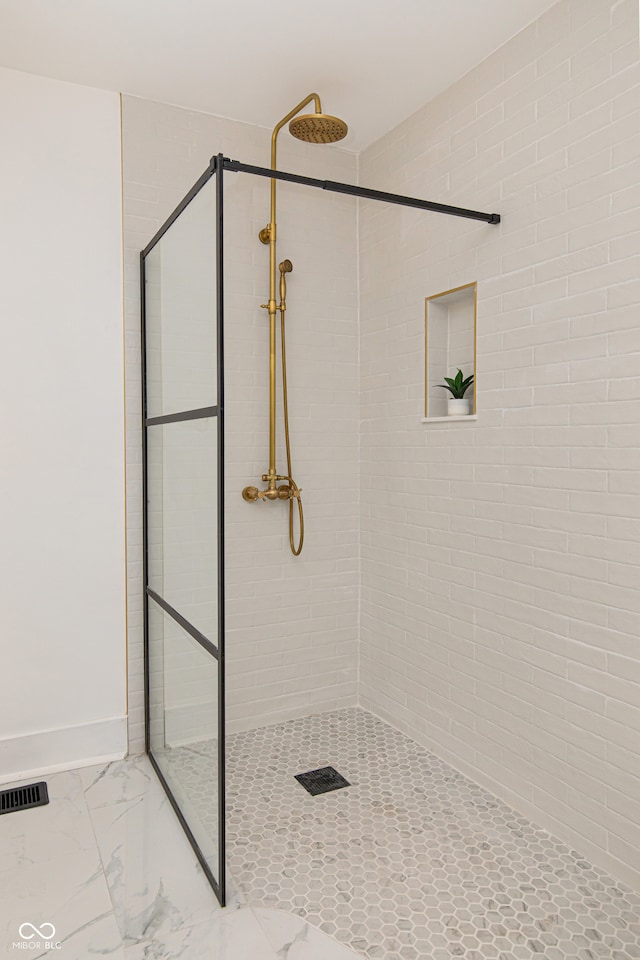 bathroom with a tile shower and tile patterned flooring