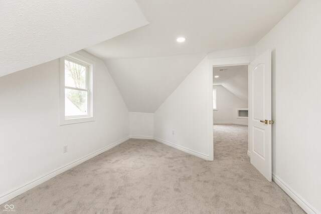 bonus room featuring light carpet, lofted ceiling, and a textured ceiling