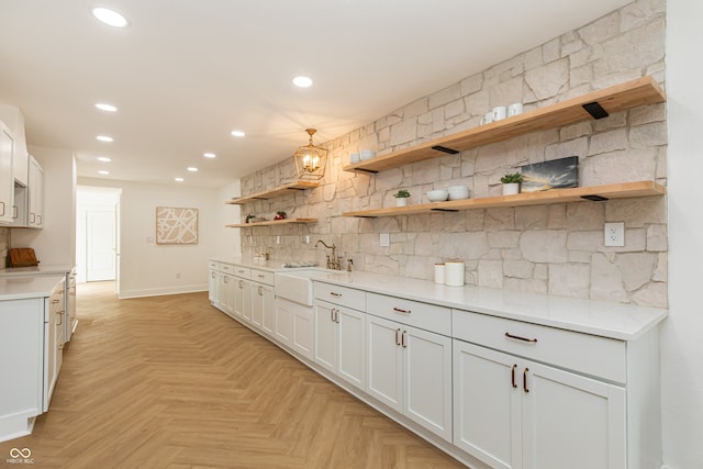 kitchen featuring white cabinetry, tasteful backsplash, light parquet floors, hanging light fixtures, and sink