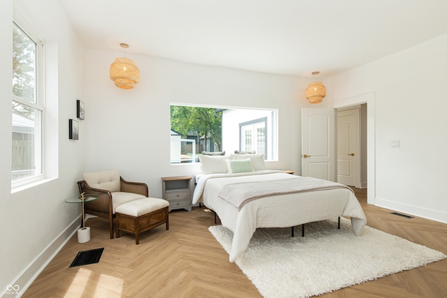 bedroom with light parquet floors and multiple windows