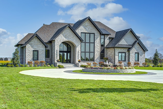 view of front facade featuring a standing seam roof, metal roof, curved driveway, and a front yard