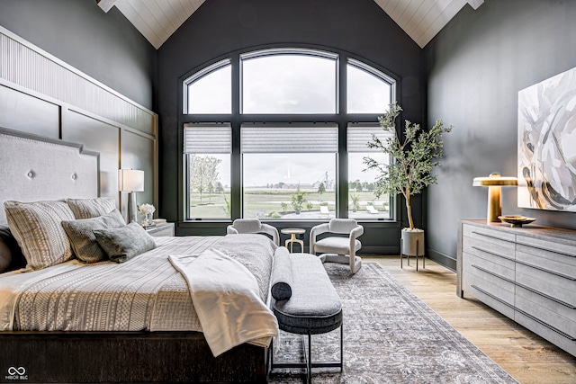 bedroom featuring light hardwood / wood-style flooring, multiple windows, and high vaulted ceiling