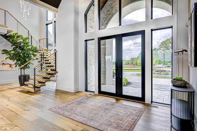 foyer with french doors, hardwood / wood-style flooring, and a towering ceiling