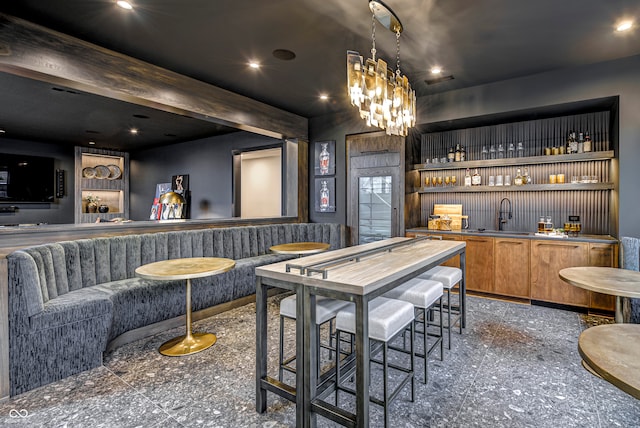 bar featuring an inviting chandelier, beamed ceiling, pendant lighting, and sink