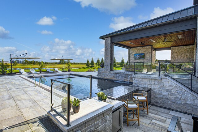 view of swimming pool with ceiling fan, exterior bar, and a patio area