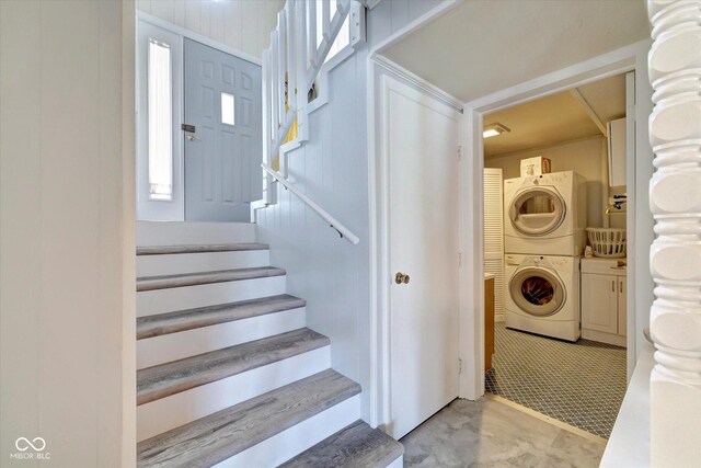 clothes washing area featuring stacked washer and dryer and cabinets