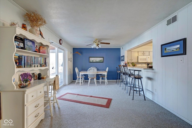 dining space with light carpet, ornamental molding, and ceiling fan