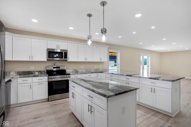 kitchen with appliances with stainless steel finishes, white cabinetry, and a kitchen island