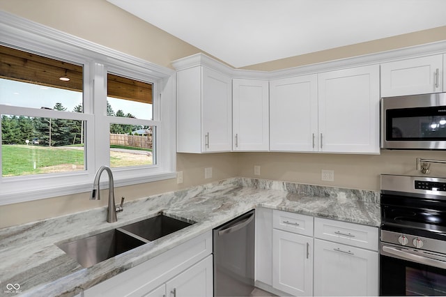 kitchen featuring sink, light stone countertops, stainless steel appliances, and white cabinets