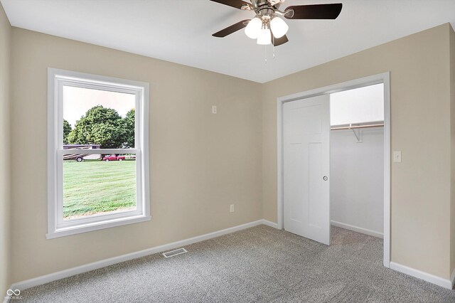 unfurnished bedroom featuring multiple windows, a closet, light colored carpet, and ceiling fan