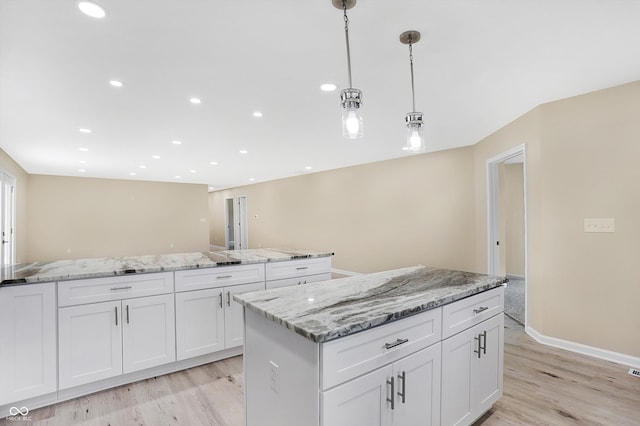 kitchen with a kitchen island, white cabinetry, light wood-type flooring, and pendant lighting