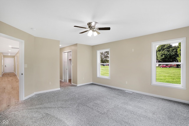 carpeted empty room with a wealth of natural light and ceiling fan