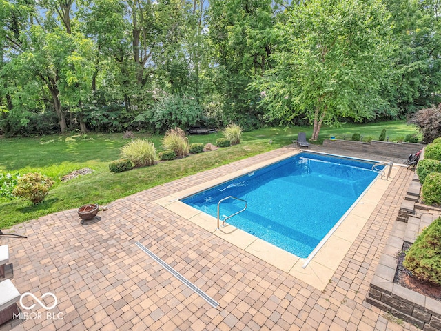 view of swimming pool featuring a lawn, a patio area, and an outdoor fire pit