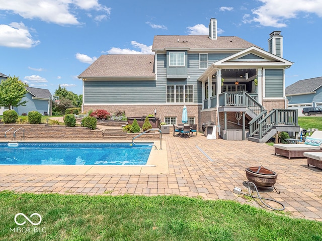 view of swimming pool with a fire pit, ceiling fan, and a patio area