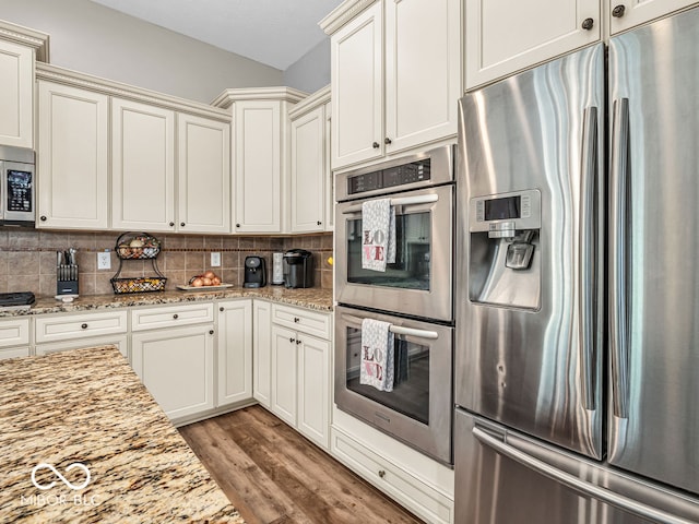 kitchen with light hardwood / wood-style floors, light stone counters, backsplash, and stainless steel appliances