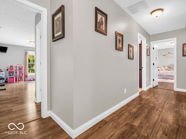 hall featuring wood-type flooring and a textured ceiling